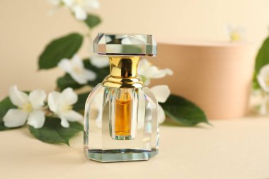 Bir şişe parfüm ve bej arka planda yasemin çiçekleri, yakın plan.