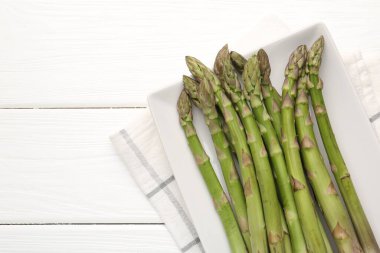 Beyaz ahşap masada taze çiğ kuşkonmaz mızrakları, üst manzara. Metin için boşluk
