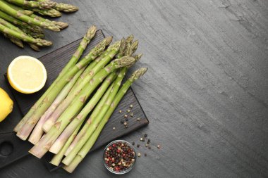 Taze çiğ kuşkonmaz mızrakları, limon ve baharatlar siyah masada, düz yerde. Metin için boşluk