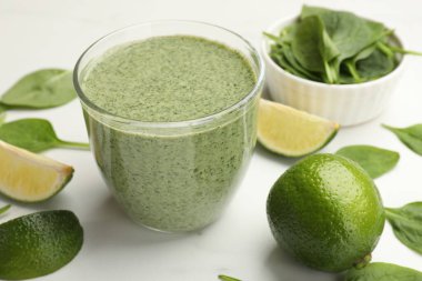 Lezzetli ıspanaklı smoothie ve malzemeler beyaz masada, yakın plan.