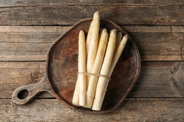 Ahşap masanın üstünde çiğ beyaz kuşkonmaz mızrakları.