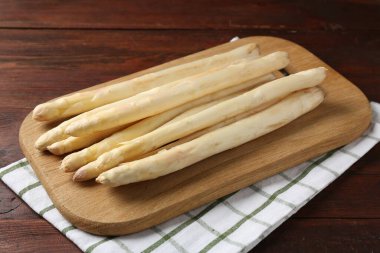 Ahşap masada çiğ kuşkonmaz mızrakları, yakın plan.