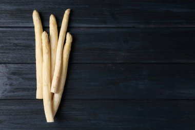 Çiğ beyaz kuşkonmaz mızrakları siyah ahşap masada, düz yerde. Metin için boşluk