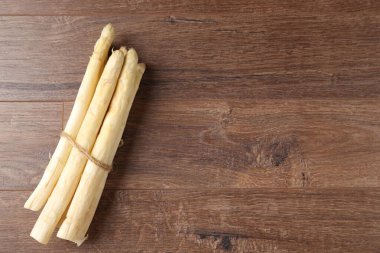 Ahşap masanın üstünde çiğ beyaz kuşkonmaz mızrakları. Metin için boşluk