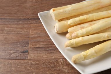 Ahşap masada çiğ beyaz kuşkonmaz mızrakları, yakın plan. Metin için boşluk