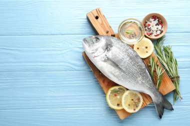 Mavi ahşap masa üzerinde baharatlı taze çiğ dourade balığı, düz ve metin için alan. Deniz ürünleri lezzetleri.