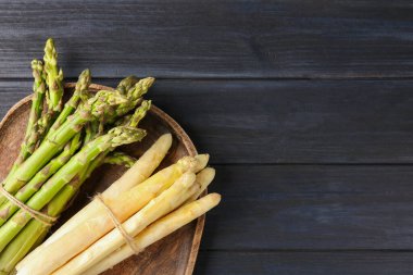 Koyu ahşap masada farklı çiğ kuşkonmaz mızrakları, üst manzara. Metin için boşluk