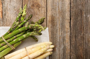 Ahşap masada farklı çiğ kuşkonmaz mızrakları, üst manzara. Metin için boşluk