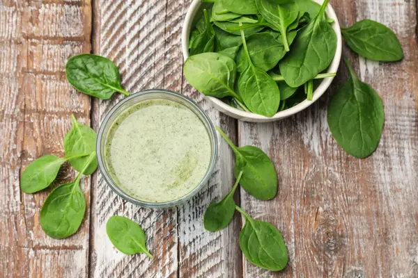 Lezzetli smoothie ve ıspanak yaprakları ahşap masada, düz yatıyordu.