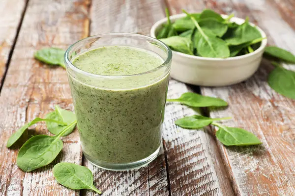 Lezzetli meyve püresi ve ıspanak yaprakları ahşap masada, yakın plan.