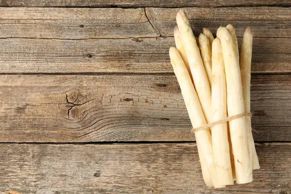 Ahşap masanın üstünde çiğ beyaz kuşkonmaz mızrakları. Metin için boşluk