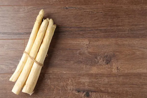 Ahşap masanın üstünde çiğ beyaz kuşkonmaz mızrakları. Metin için boşluk