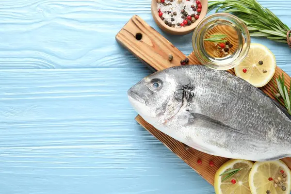 Mavi ahşap masa üzerinde baharatlı taze çiğ dourade balığı, düz ve metin için alan. Deniz ürünleri lezzetleri.
