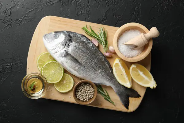 Siyah masadaki baharatlı taze çiğ dourade, üst manzara. Balık ve deniz ürünleri lezzetleri