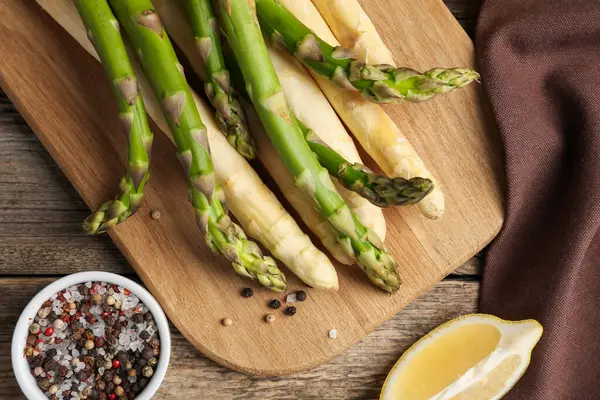 Ahşap masada farklı çiğ kuşkonmaz ve baharatlar var.