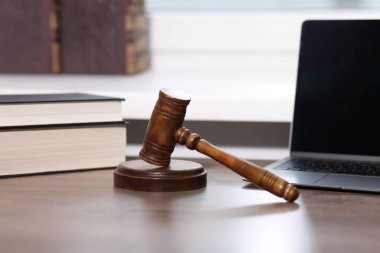 Yargıç. Ofisteki tahta masada dizüstü bilgisayar, tokmak ve kitaplar.