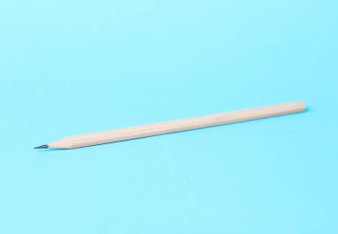 Açık mavi arkaplanda bir grafit kalem, yakın plan.