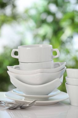 Bulanık yeşil arka planda beyaz masada farklı temiz tabaklar