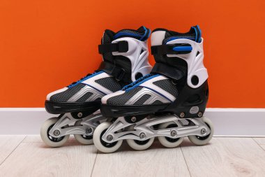 Turuncu duvarın yanında yerde bir çift paten var.