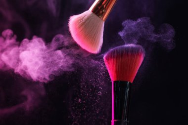 Renkli göz gölgeli makyaj fırçaları siyah arka planda neon ışıkları, yakın plan