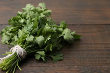 Ahşap masada taze aromatik kişniş demeti, yakın plan. Metin için boşluk