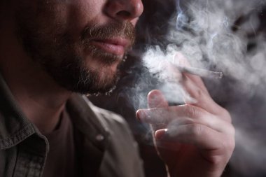 Arka planda sigara içen adam, yakın plan.