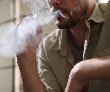 Arka planda sigara içen adam, yakın plan.