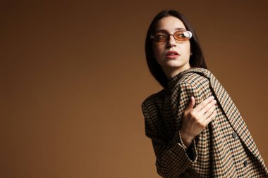 Kahverengi arka planda şık giyinmiş güzel bir kadının portresi.