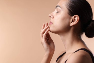 Bej arka planda dudak kremi olan genç bir kadın, mesaj için yer var.