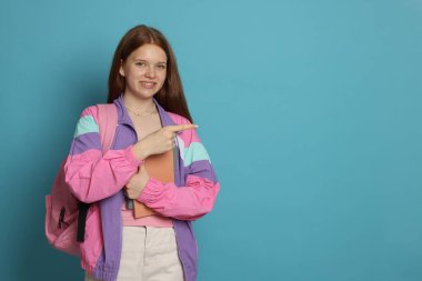 Kitapları açık mavi arka planda bir şeye bakan genç kız. Metin için boşluk