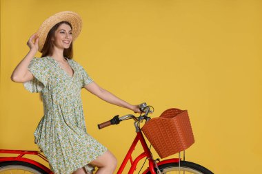 Sarı arka planda sepeti olan şapkalı, gülen bir kadın. Metin için boşluk