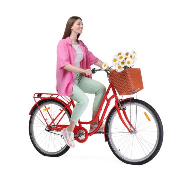 Gülen kadın, beyaz arka planda çiçek dolu bir sepetle bisiklet sürüyor.