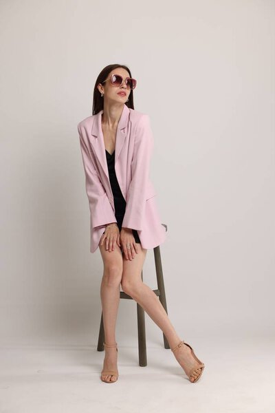 Beautiful woman in stylish outfit sitting on chair against white background