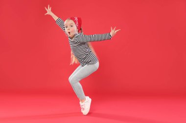 Kırmızı arka planda dans eden tatlı küçük kız, mesaj için yer.