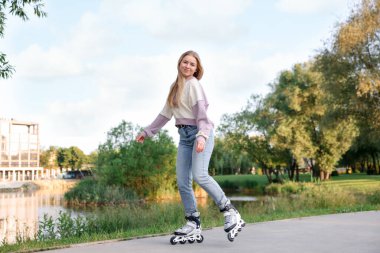 Güzel genç bir kadın parkta paten kayıyor.