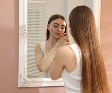 Güzel genç bayan aynanın yanında poz veriyor.