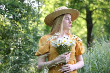Ormanda bir buket kır çiçeğiyle güzel bir kadın