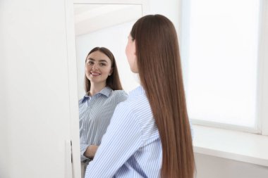 Güzel bir kadın aynada kendine bakıyor.