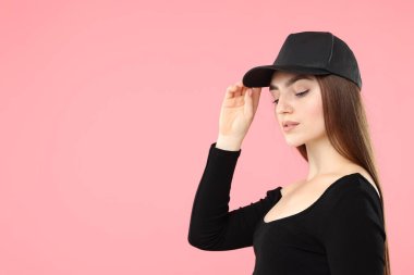 Pembe arka planda şık bir beyzbol şapkası olan güzel bir kadın. Metin için boşluk