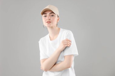 Gri arka planda şık beyzbol şapkalı güzel bir kadın.