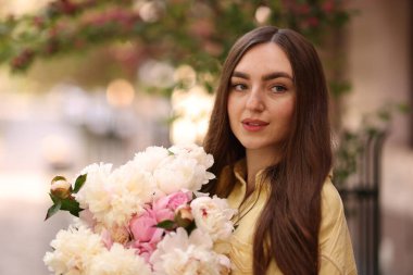 Şehir caddesinde elinde şakayık demeti olan bir kadın