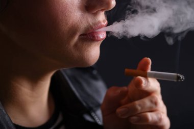 Siyah arka planda sigara içen kadın, yakın plan.