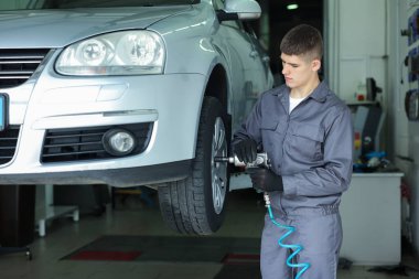 Araba servisinde lastik değiştiren profesyonel bir tamirci.