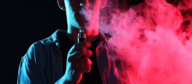 Siyah arka planda neon lambalarda elektronik sigara içen adam, yakın plan