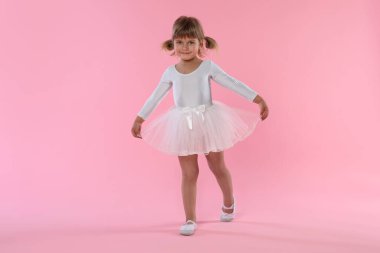 Pembe arka planda dans eden tatlı küçük kız.