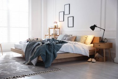 Yumuşak çarşaflı rahat bir yatak, şık bir odada komodin ve lamba. Ev tekstili