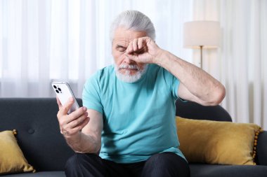 Evdeki kanepede akıllı telefon kullanan görme sorunu olan son sınıf öğrencisi.