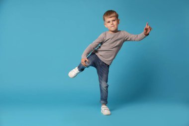 Açık mavi arka planda dans eden mutlu küçük çocuk, mesaj için boşluk