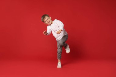 Kırmızı arka planda dans eden küçük mutlu çocuk