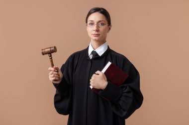 Açık kahverengi arkaplan üzerine kitap ve çekiçle yargıç